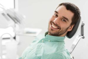 A dentist examines a patient's teeth in a clean, modern dental office, using gloves and an overhead light.