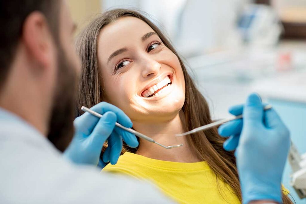Adult and child brushing teeth together at a bathroom sink with toothbrushes, toothpaste, and dental floss nearby.